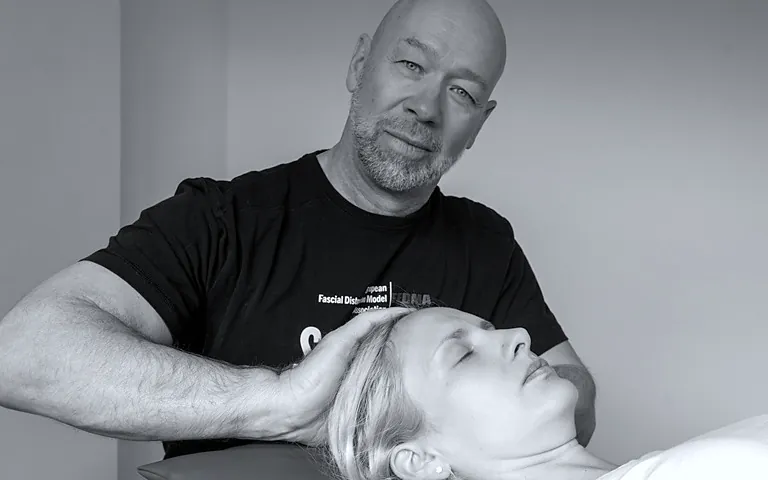 Kopfschmerzbehandlung nach dem Scalp-Concept® in Rückenlage: Physiotherapeut behandelt die Kopfhaut einer Patientin