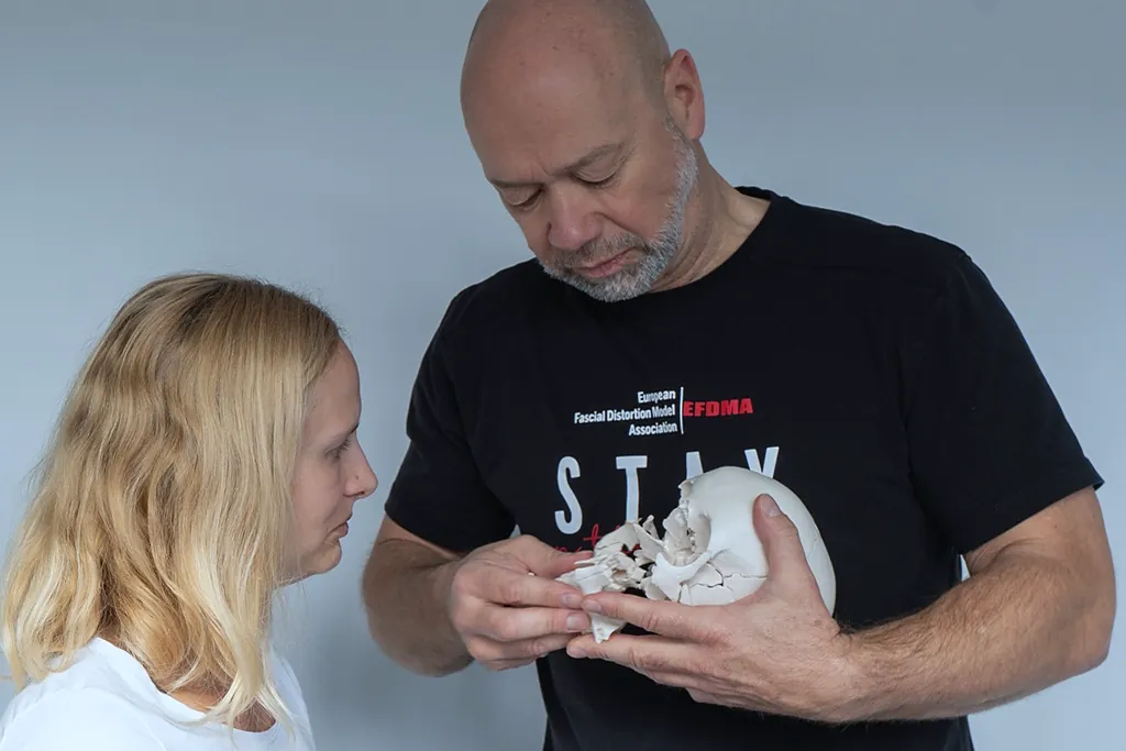 Physiotherapeut erklärt einer Patientin die Behandlung am Schädelmodell